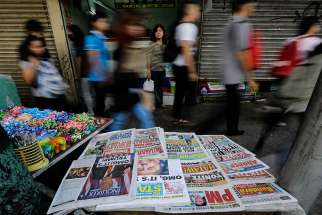  In this 2016 file photo, Filipinos walk past a newspaper stand in Manila, Philippines. A Philippine church official urged about 150 priests, women religious and lay people working in Catholic media to confront &quot;fake news&quot; during the annual National Catholic Media Convention Aug. 6-9 in Davao City. 